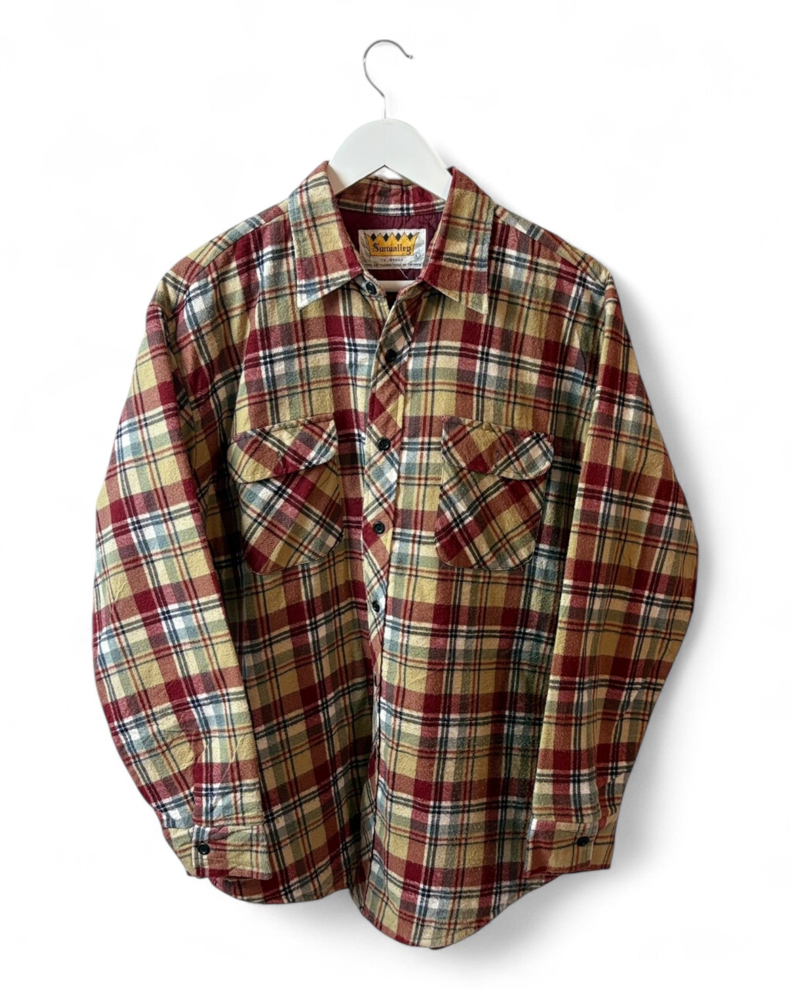 Plaid shirt on a hanger against a white background